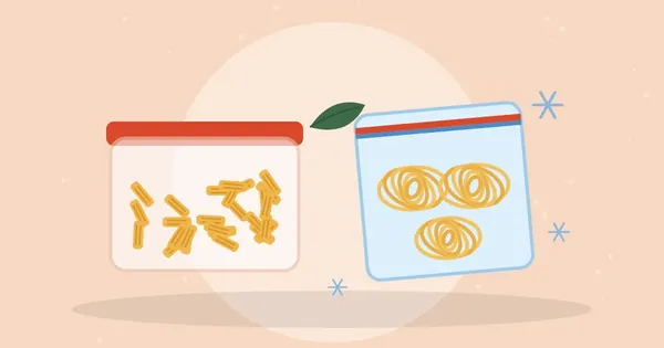 Glass container of cooked penne pasta beside a freezer bag holding spaghetti nests