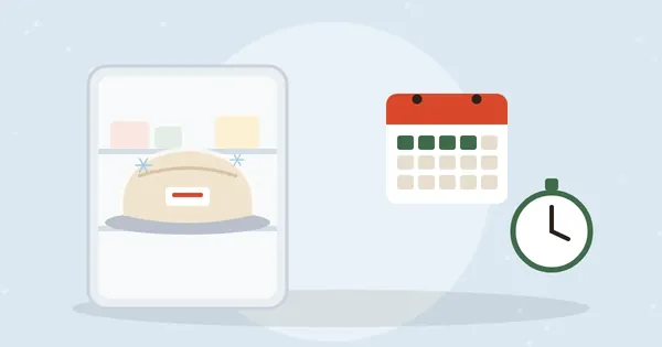 Frozen wrapped turkey on a refrigerator shelf next to a calendar and a timer